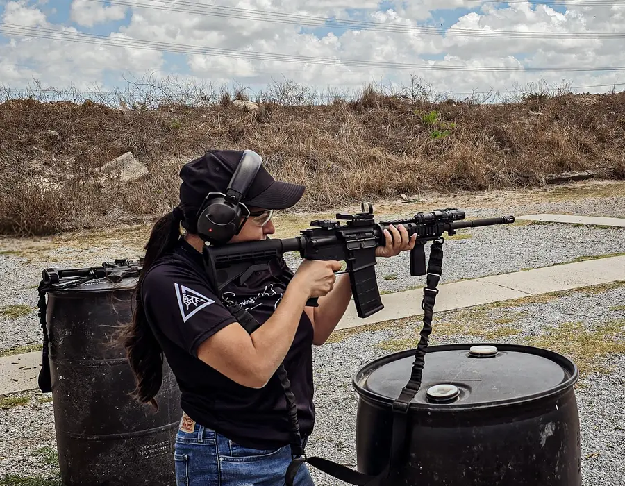 A student shooting a rifle from a standing position at an outdoor range in Brownsville