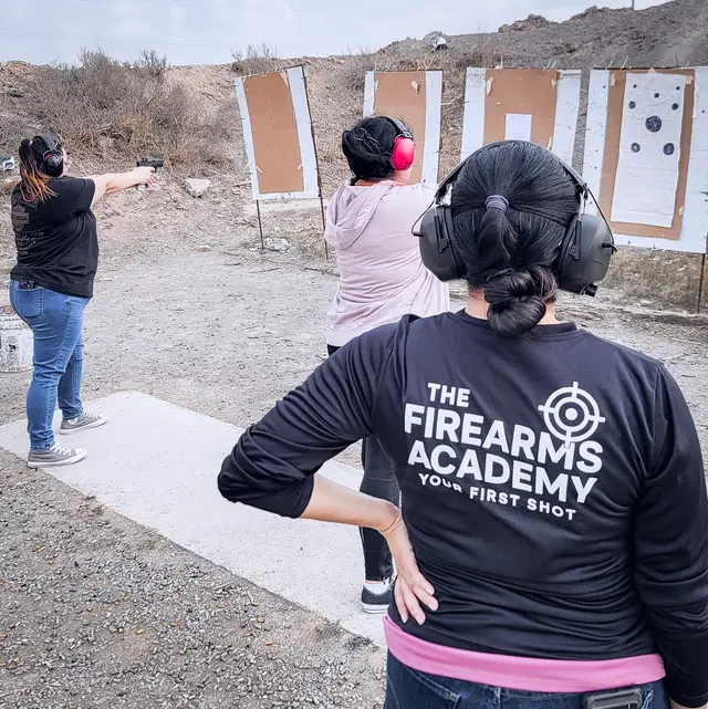 A Firearms Academy instructor supervising women students shooting at silhouette targets on an outdoor range